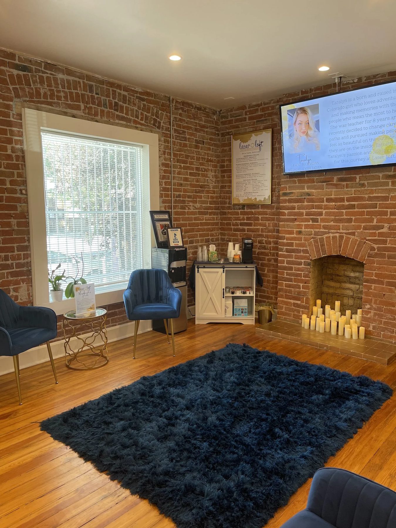 The Denver front room, window, brick fireplace and blue chairs